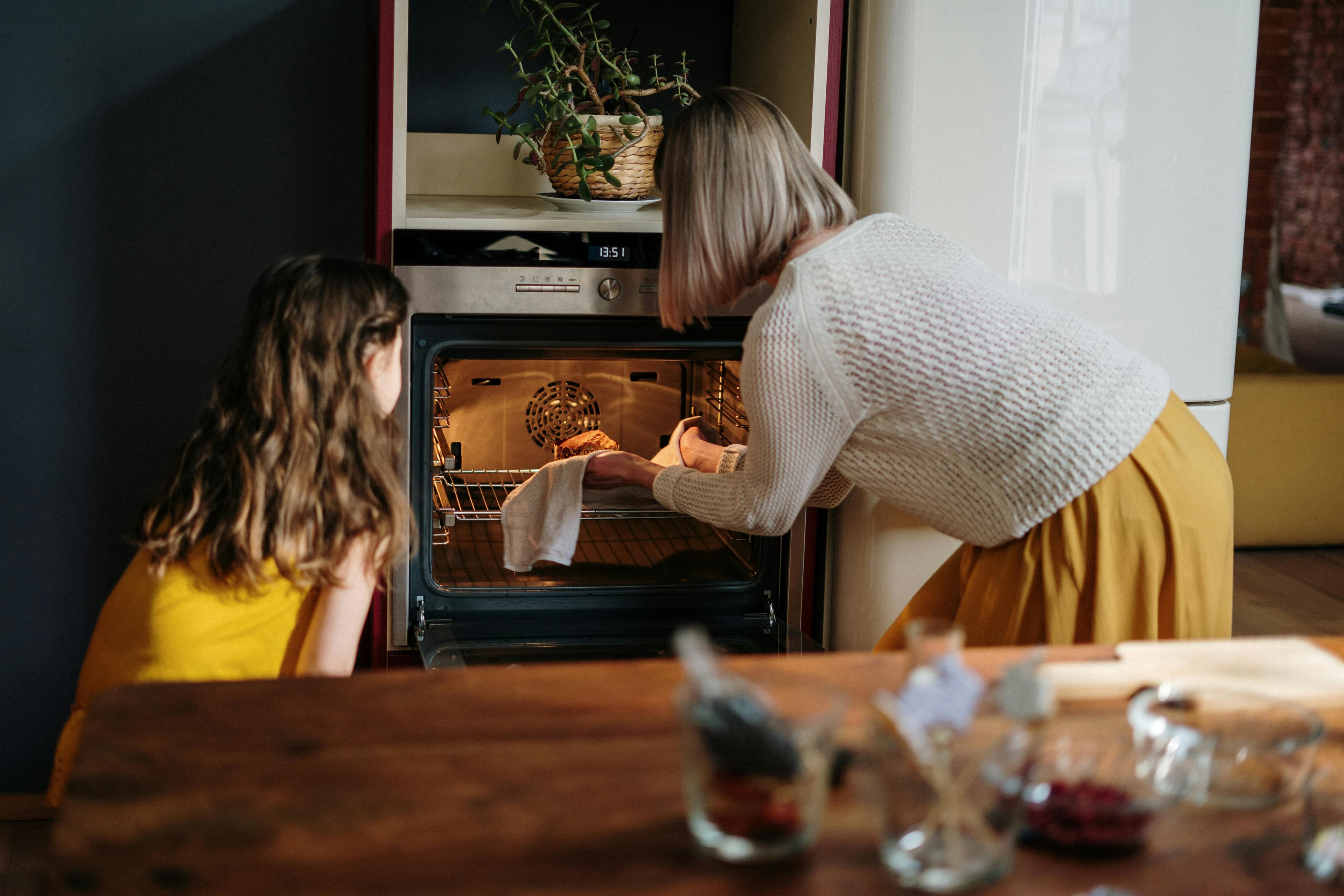 Mother and daughter in the kitchen, looking into oven.